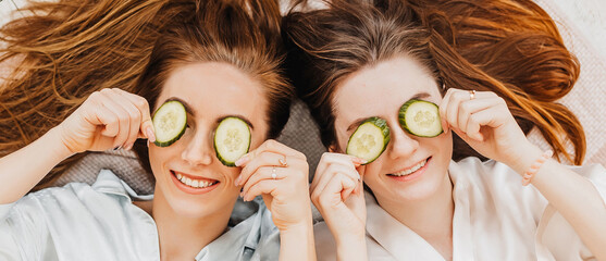 Wall Mural - two girls make homemade face and hair beauty masks. cucumbers for the freshness of the skin around t