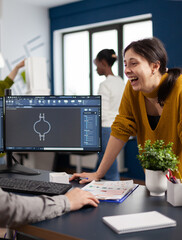 Wall Mural - Excited mechanical engineers laughing and discussing about manufacturing new project, taking break. Man technician working at pc, screen shows 3D engine made with CAD software, using computer