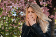 © New Africa - Woman suffering from seasonal pollen allergy near blossoming tree outdoors
