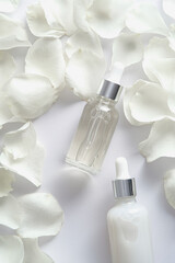 Wall Mural - Essential oil bottles and rose petals on white background. Flat lay, top view.