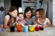 © natalialeb - Home experiments with different colors, food dyes. Children play with colored water. Four children are experimenting with colorful drinks at the table.