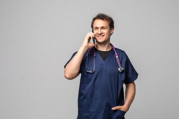 Portrait of successful doctor talking on phone. Smiling medical doctor with stethoscope talking on his cell phone, on white background. Concept of medical phone consultation.