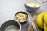 Fototapeta  - Płatki owsiane, jogurt naturalny w miskach. Przygotowanie zdrowego śniadania.