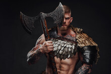 Brutal Tattooed Warrior Wearing Light Armour And Fur Holding Two-handed Axe In Dark Studio