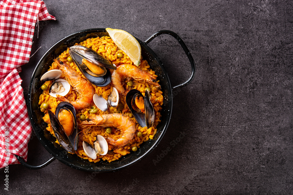 Traditional spanish seafood paella on black background. Top view. Copy space - obrazy, fototapety, plakaty 