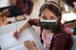 © Wavebreak Media - Portrait of caucasian wearing face mask sitting on her desk in the class at school