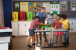 © Wavebreak Media - Caucasian male teacher and students putting recyclable plastic items in tray at school