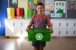 © Wavebreak Media - Portrait of caucasian boy smiling while holding tray filled with recyclable plastic items at school
