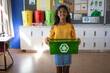 © Wavebreak Media - Portrait of african american girl holding tray filled with recyclable plastic items at school
