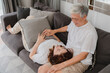 © tirachard - Asian senior couple relax at home. Asian Senior Chinese grandparents, husband happy smile hug lie down her wife lap while lying on sofa in living room at home concept.