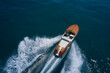 © Berg - Classic Italian wooden boat fast moving aerial view. Top view of a wooden powerful motor boat. Luxurious wooden boat fast movement on dark water.
