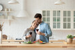 © fizkes - Calm mixed-race spouses hugging in kitchen with wine glasses. Couple celebrate anniversary, special occasion, enjoy dating together at home. Romantic relations, St. Valentines Day celebrations concept