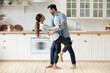 © fizkes - Young beautiful mixed race couple home owners family celebrate relocation day housewarming dancing in modern cozy kitchen standing barefoot on warm floor feel happy. Romance, dating, bank loan concept