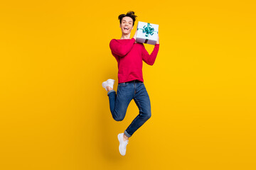 Poster - Full length photo of charming funky young gentleman wear red sweater jumping holding gift isolated yellow color background