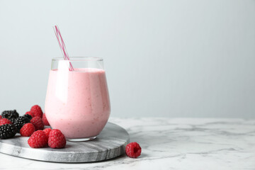 Wall Mural - Yummy berry smoothie in glass on white marble table, space for text