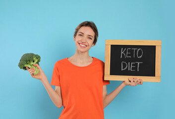 Wall Mural - Woman holding blackboard with phrase Keto Diet and broccoli on light blue background