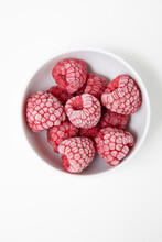 Frozen Raspberries In A White Bowl On A White Background