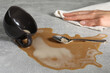 Woman wiping spilled coffee on grey table, closeup