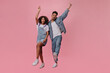 © Look! - Woman in denim jumpsuit and guy in jeans rejoice on pink background. Happy dark-skinned man in blue jacket and curly girl in white tee dance and move on isolated