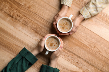 Poster - Women with cups of coffee at wooden table, top view