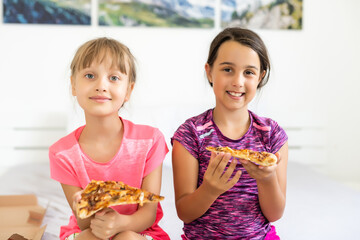 Two pretty young girls eating a slice of pizza