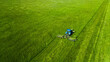A blue tractor mowing a bright green field, aerial view. Agricultural shade in summer.