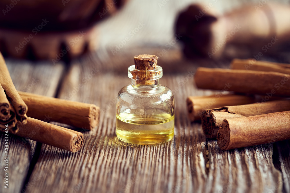 A bottle of aromatherapeutic essential oil with Ceylon cinnamon sticks - obrazy, fototapety, plakaty 