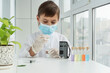 © Anna - Boy in  mask, gloves and  white coat holding  pipette and lab glass before examining with a microscope. Scientifical experiments at home, research concept.