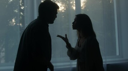 silhouettes of man and woman shouting at each other, couple quarreling in the evening at home husban
