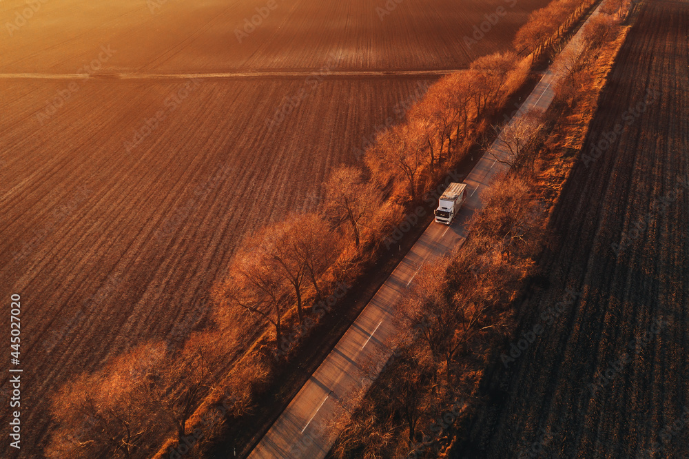 Aerial view of semi-truck on the road in sunset, drone pov - obrazy, fototapety, plakaty 