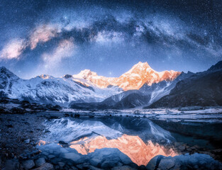Wall Mural - milky way over snowy mountains and lake at night. landscape with snow covered high rocks, starry sky