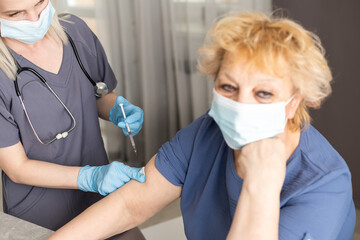 Wall Mural - Doctors are vaccinating an elderly woman in a white shirt to build up the coronavirus or COVID-19 immune system