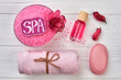 Flat lay pink spa accessories on white wooden desk.