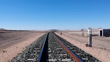 Very Low Down View Of Railway Tracks In A Desert Small Building On Right Side Of Track Landscape Aerial Video.