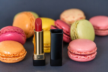 Wall Mural - Macarons on dark background, colourful french cookies macarons and red classical lipstick 