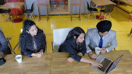 Wall Mural - High angle shot of two South Asian males and two females discussing business indoors