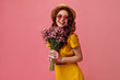 © Look! - Portrait of red haired woman in boater holding pink flowers. Charming girl with wavy hair in wide-brimmed hat posing with bouquet