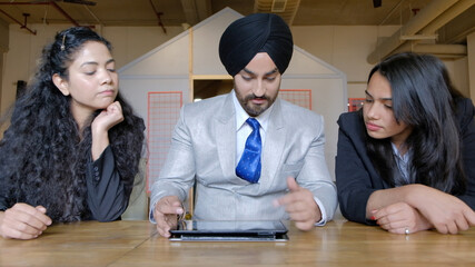 Wall Mural - Closeup shot of a South Asian male and two females discussing business indoors