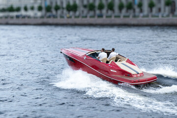 Two men are sailing on a red boat on the river