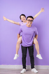 Wall Mural - Young Asian couple posing on purple background