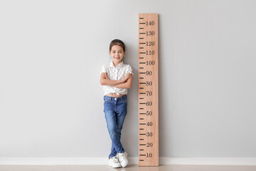 Poster - Little girl measuring height near light wall