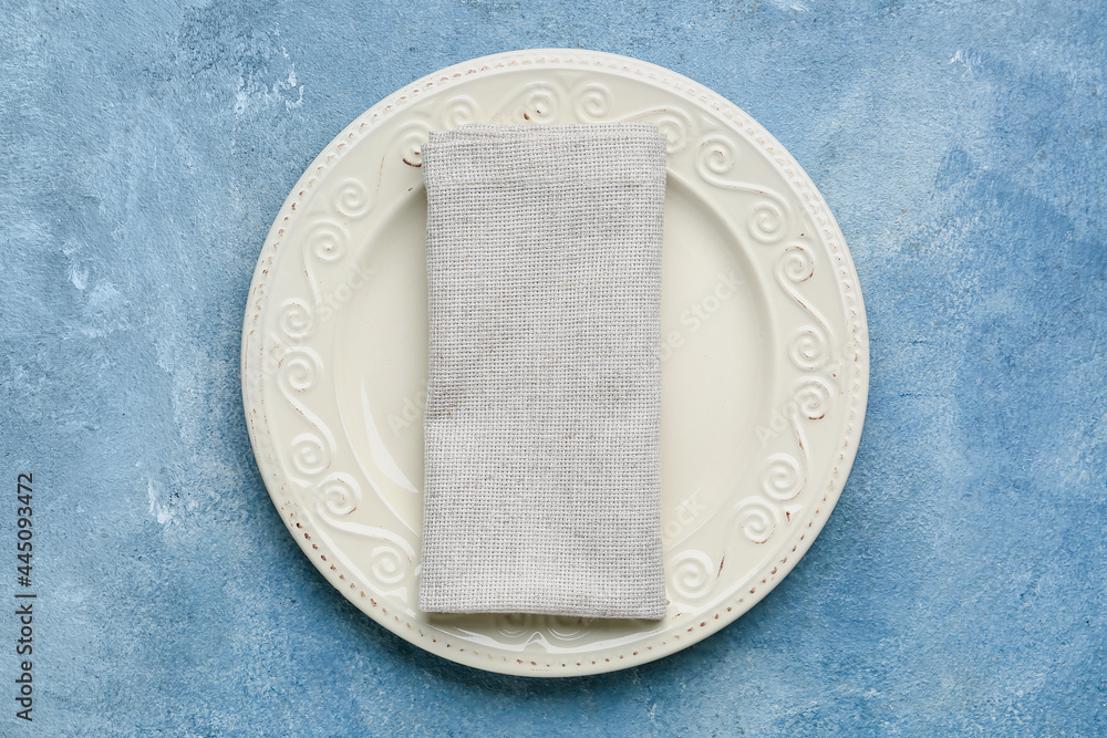Fabric napkin and plate on color background