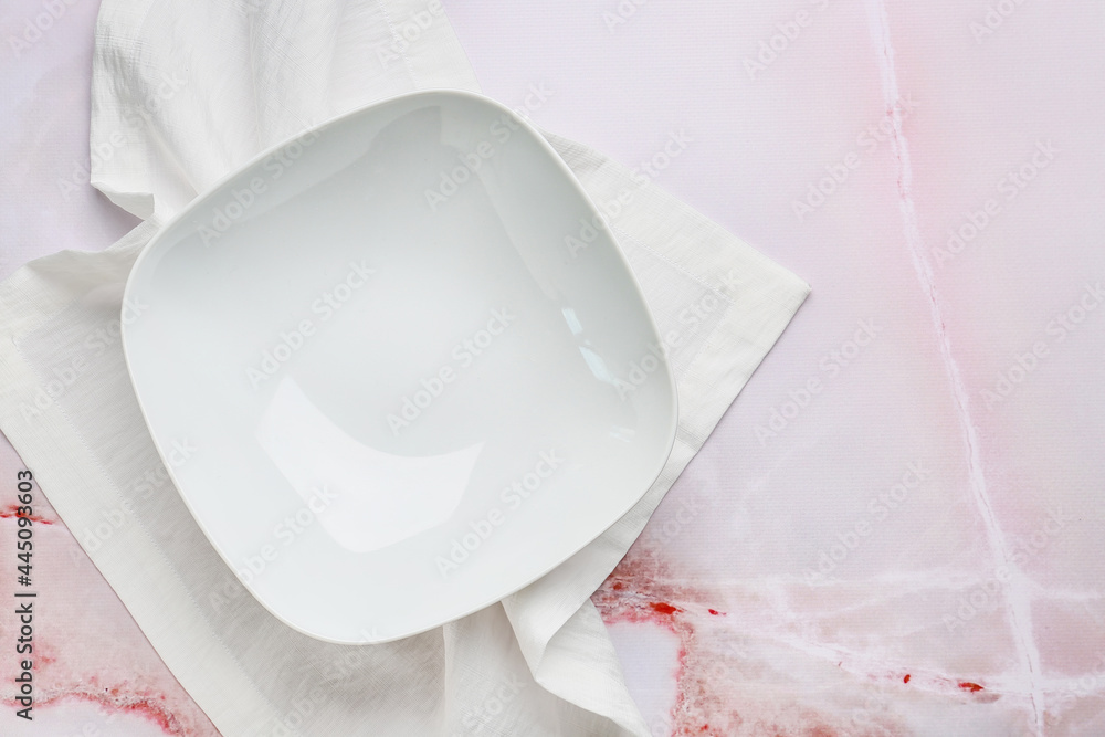 Fabric napkin and bowl on color background