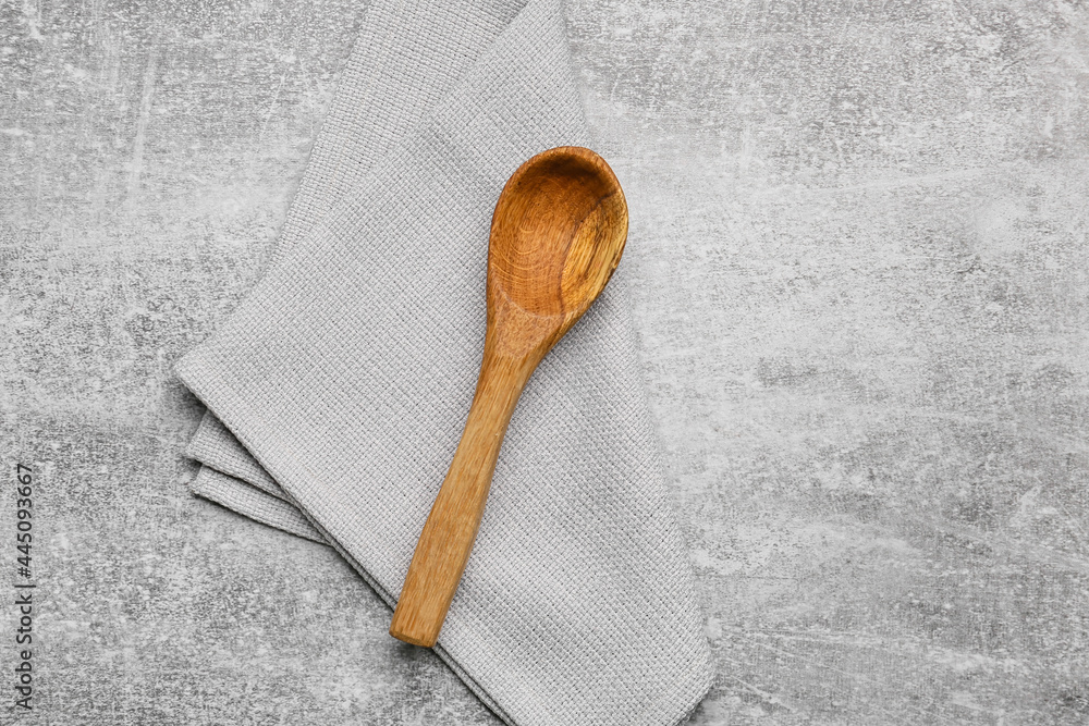 Fabric napkin and wooden spoon on grunge background