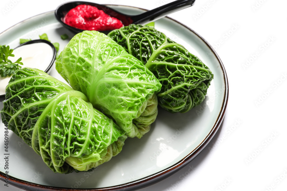 Plate with stuffed cabbage leaves, sour cream and sauce on white background, closeup