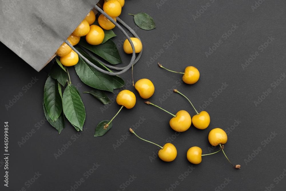 Bag with tasty sweet cherries on dark background