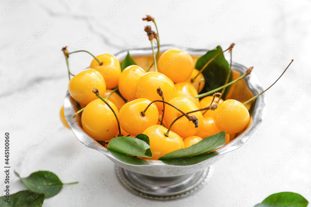 Bowl with tasty sweet cherries on light background