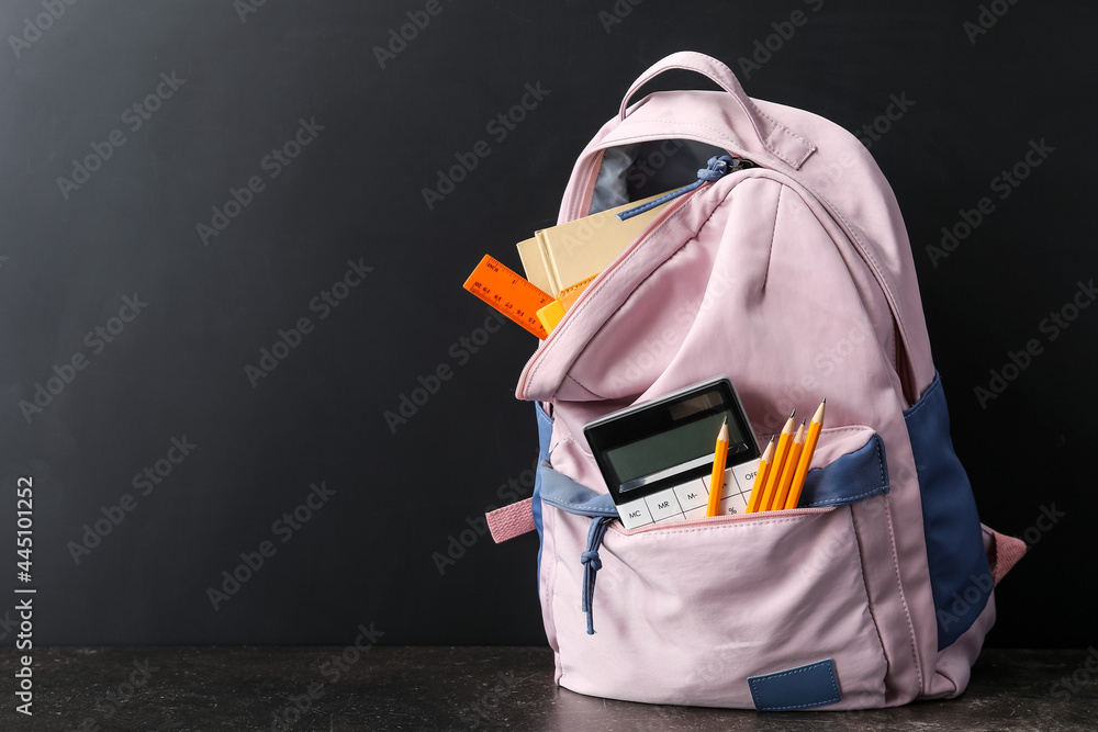 School backpack and stationery near blackboard