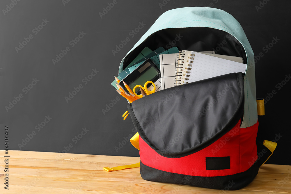 School backpack and stationery on table near blackboard - obrazy, fototapety, plakaty 