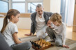 © zinkevych - Siblings playing chess while their father watching